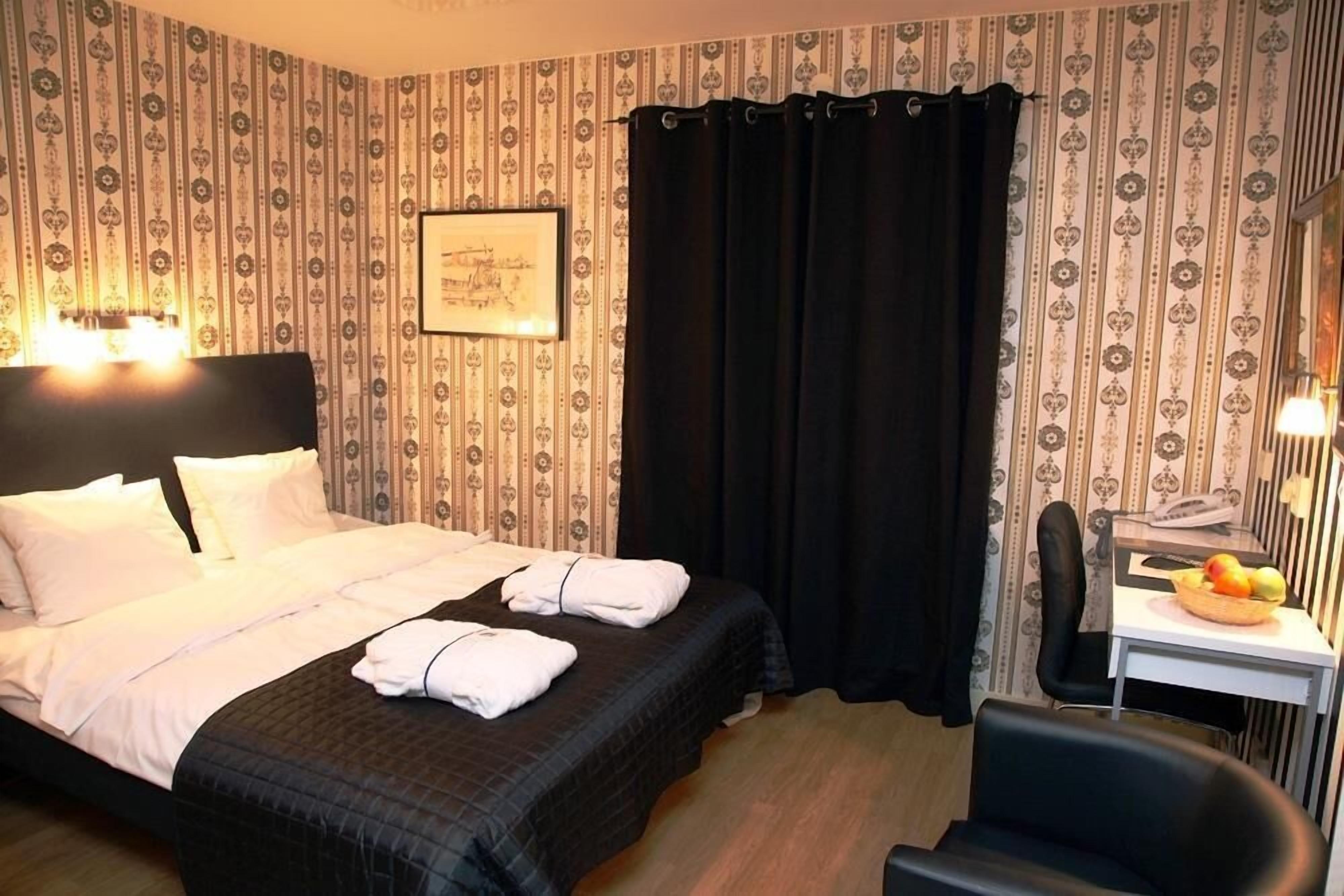 Een hotelkamer met een bed, een bureau met stoel, een telefoon en een fruitmand.