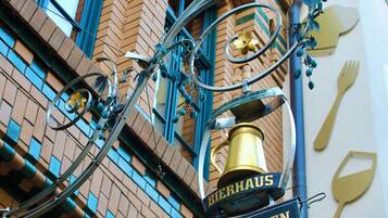 Fachada d'un edifici amb un rètol que diu "Bierhaus Biergarten" i una estructura metàl·lica decorativa.