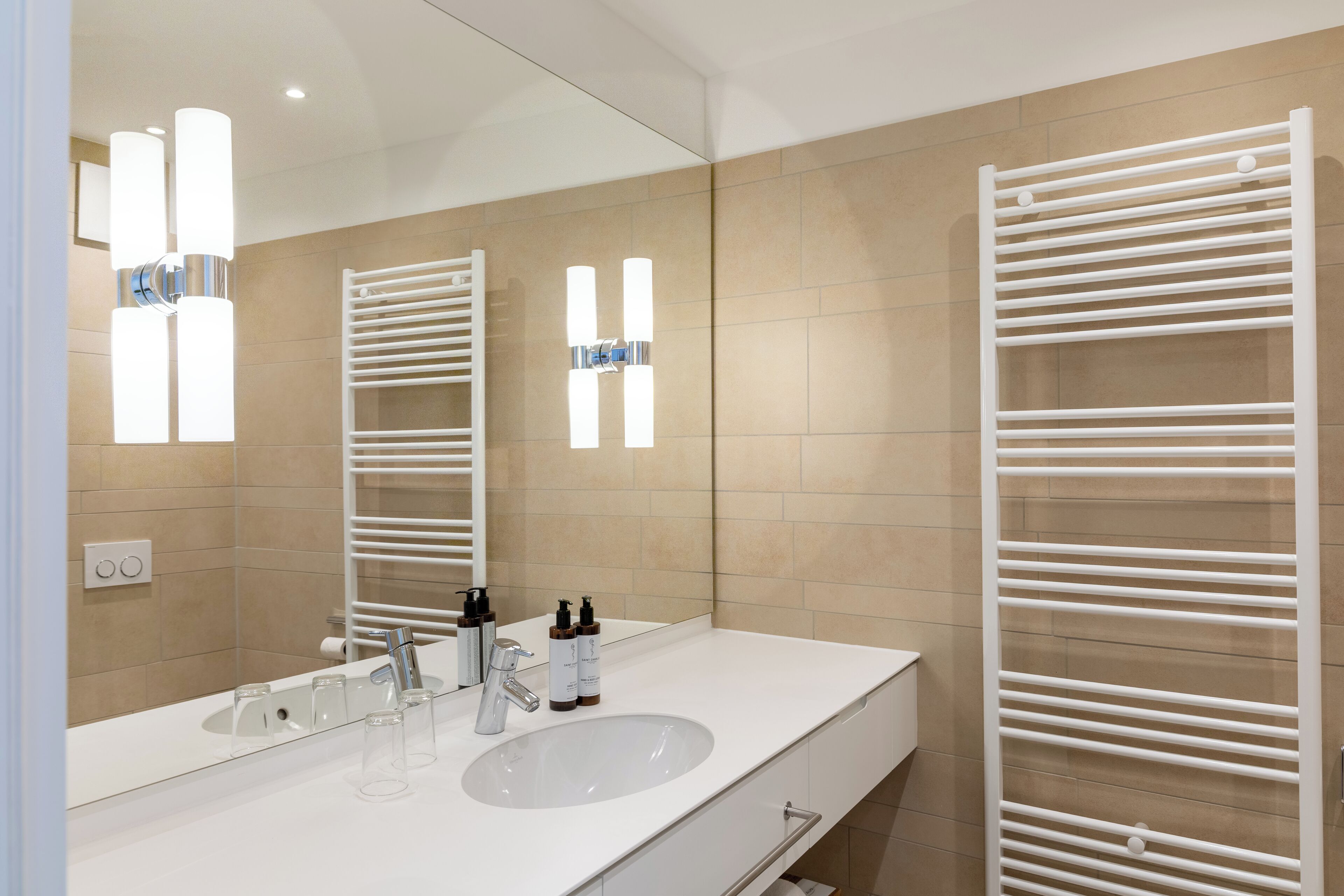 A modern bathroom with a large mirror, two sinks, and a towel rack.