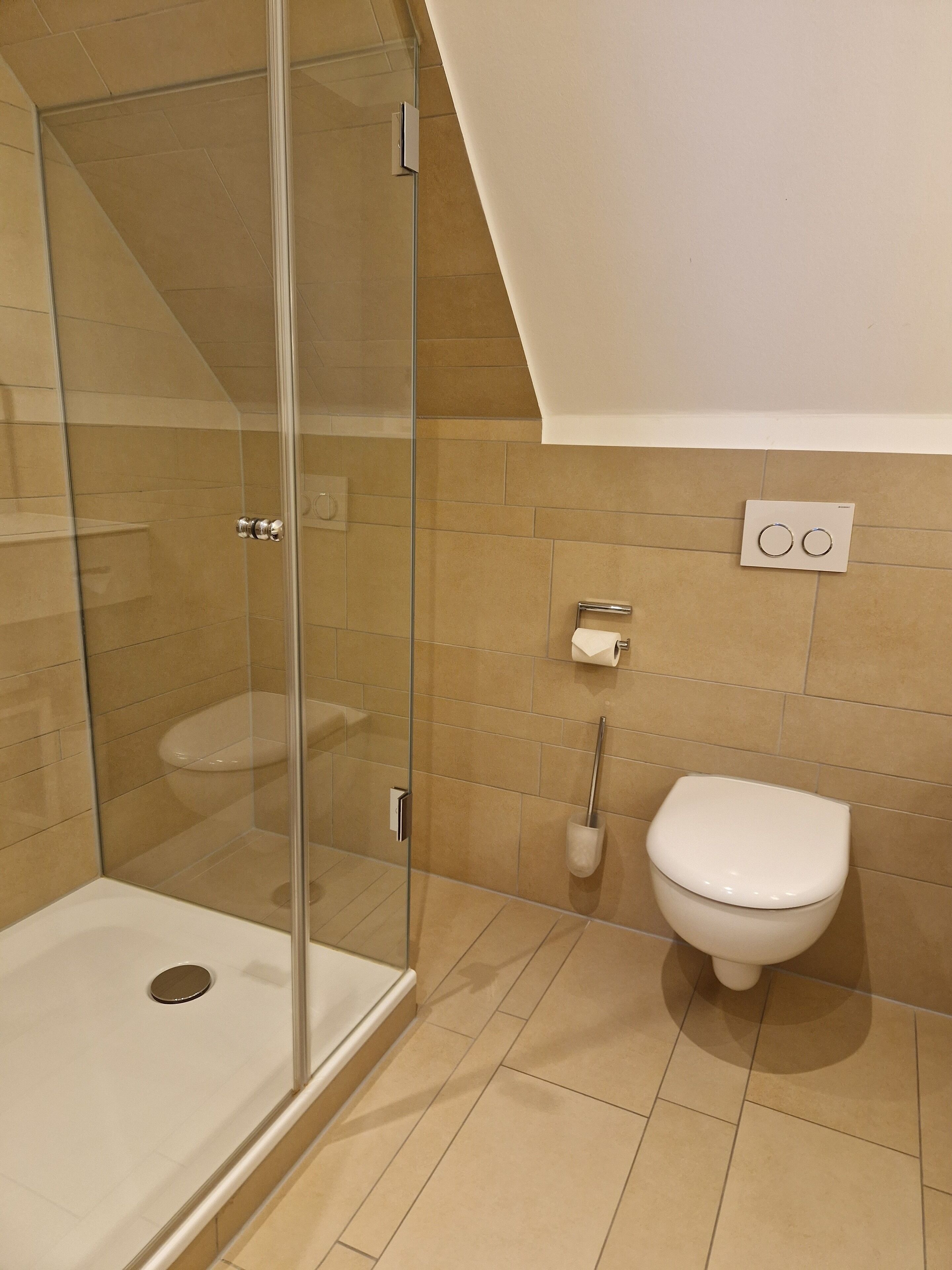 Un baño moderno con cabina de ducha de vidrio, inodoro blanco y toallero.