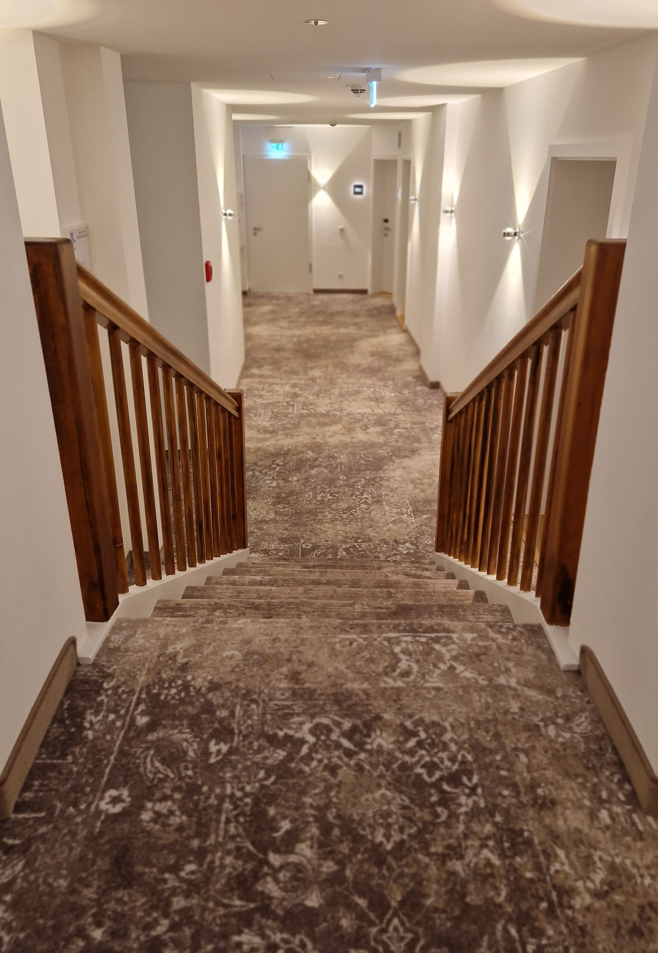 A carpeted staircase with wooden railings leading to a door at the top.