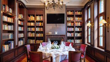 A library with bookshelves, a fireplace, and a dining table set for four.