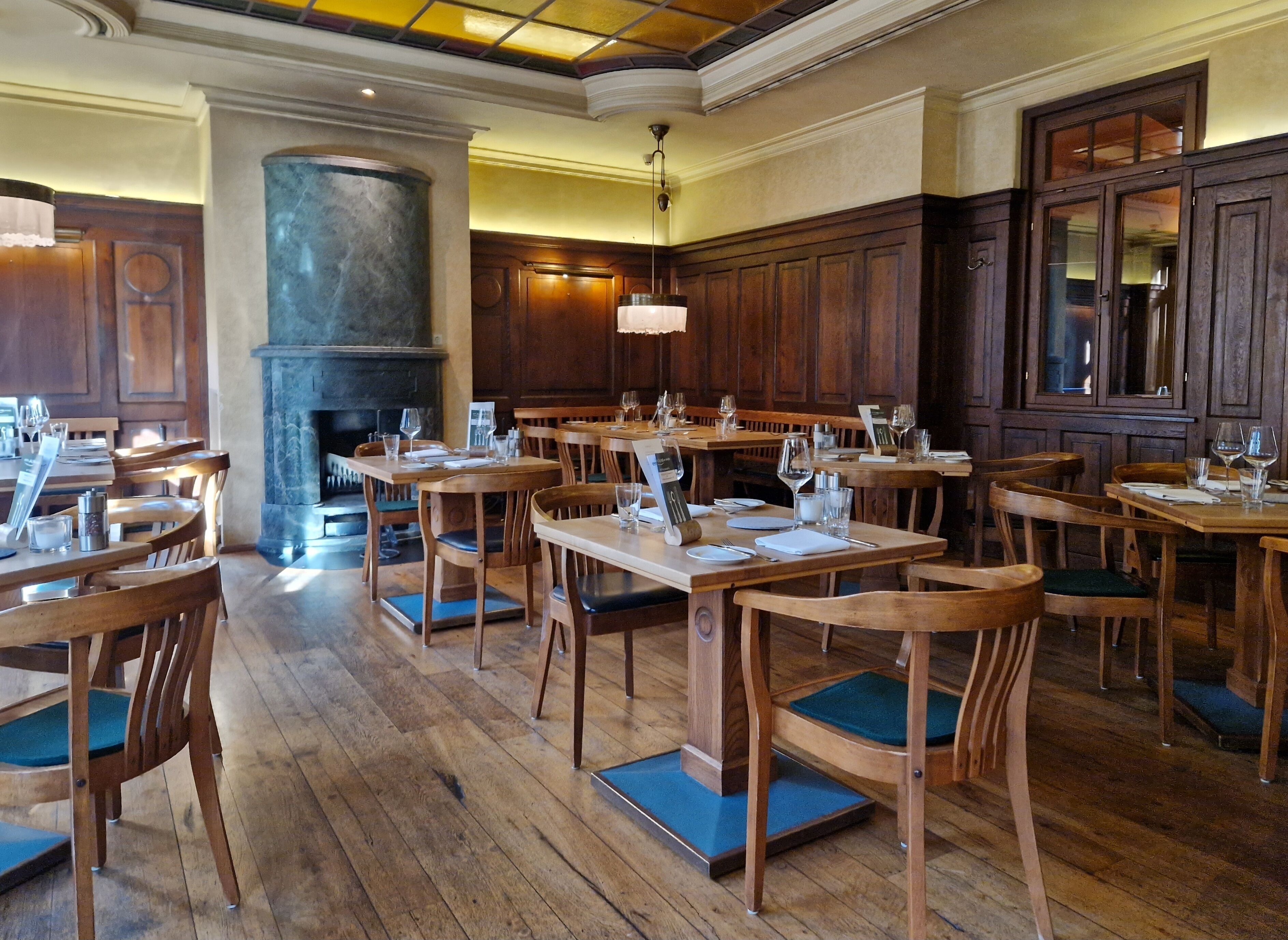 A restaurant with wooden tables and chairs, a stone pillar, and a fireplace.