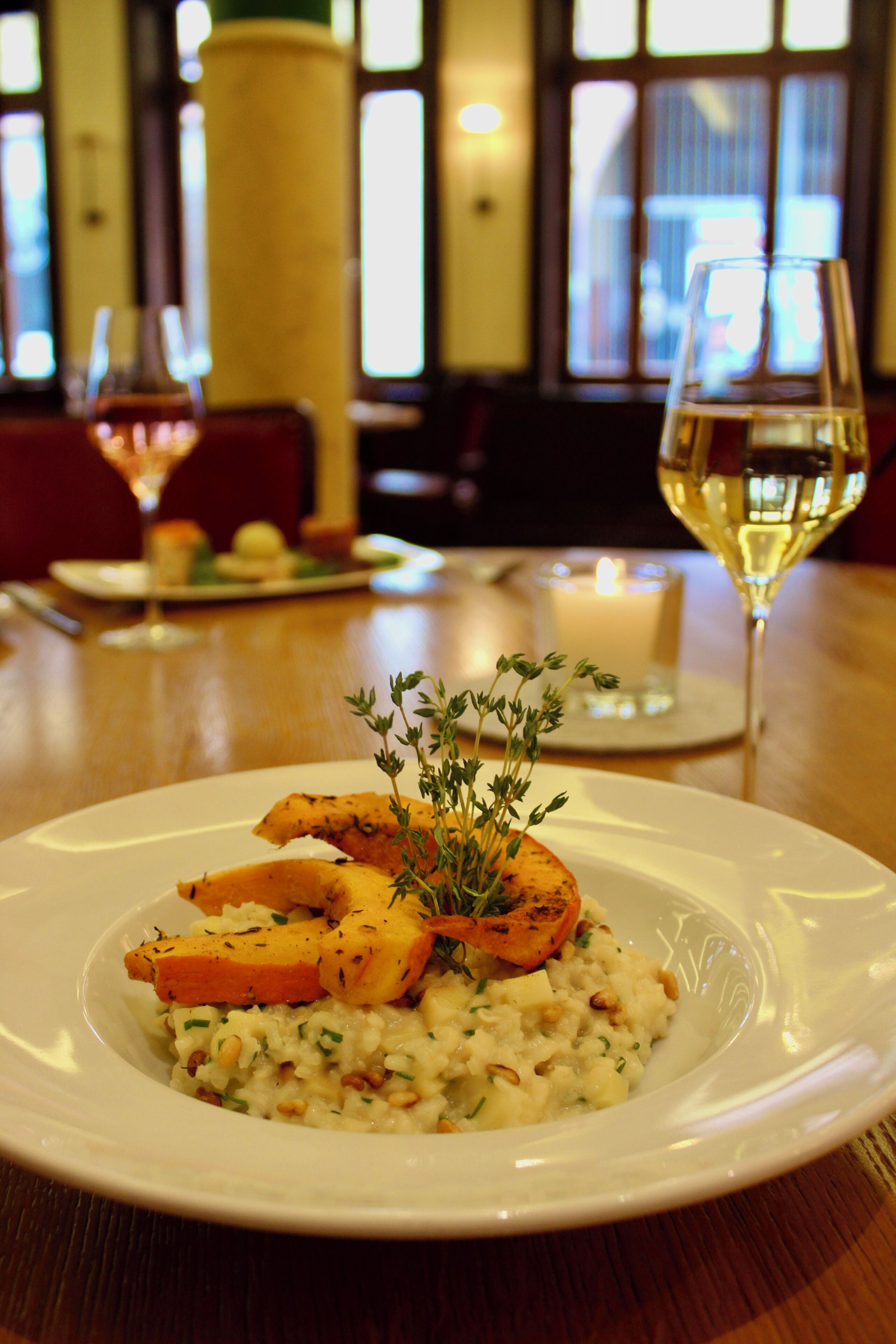 Une table à manger avec une assiette de nourriture, une bougie et des verres de vin.