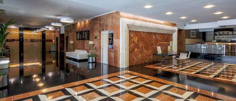 A lobby with a geometric patterned floor, a reception desk, and a bar area.
