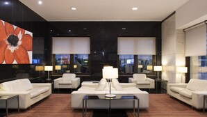 A modern hotel lobby with a central seating area, large windows, and a prominent artwork. - SANA Metropolitan Hotel (Lisbon)