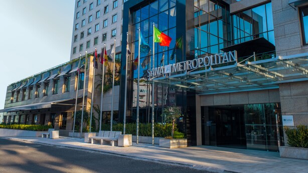 A modern hotel with a glass facade, multiple flags, and a prominent entrance. - SANA Metropolitan Hotel (Lisbon)