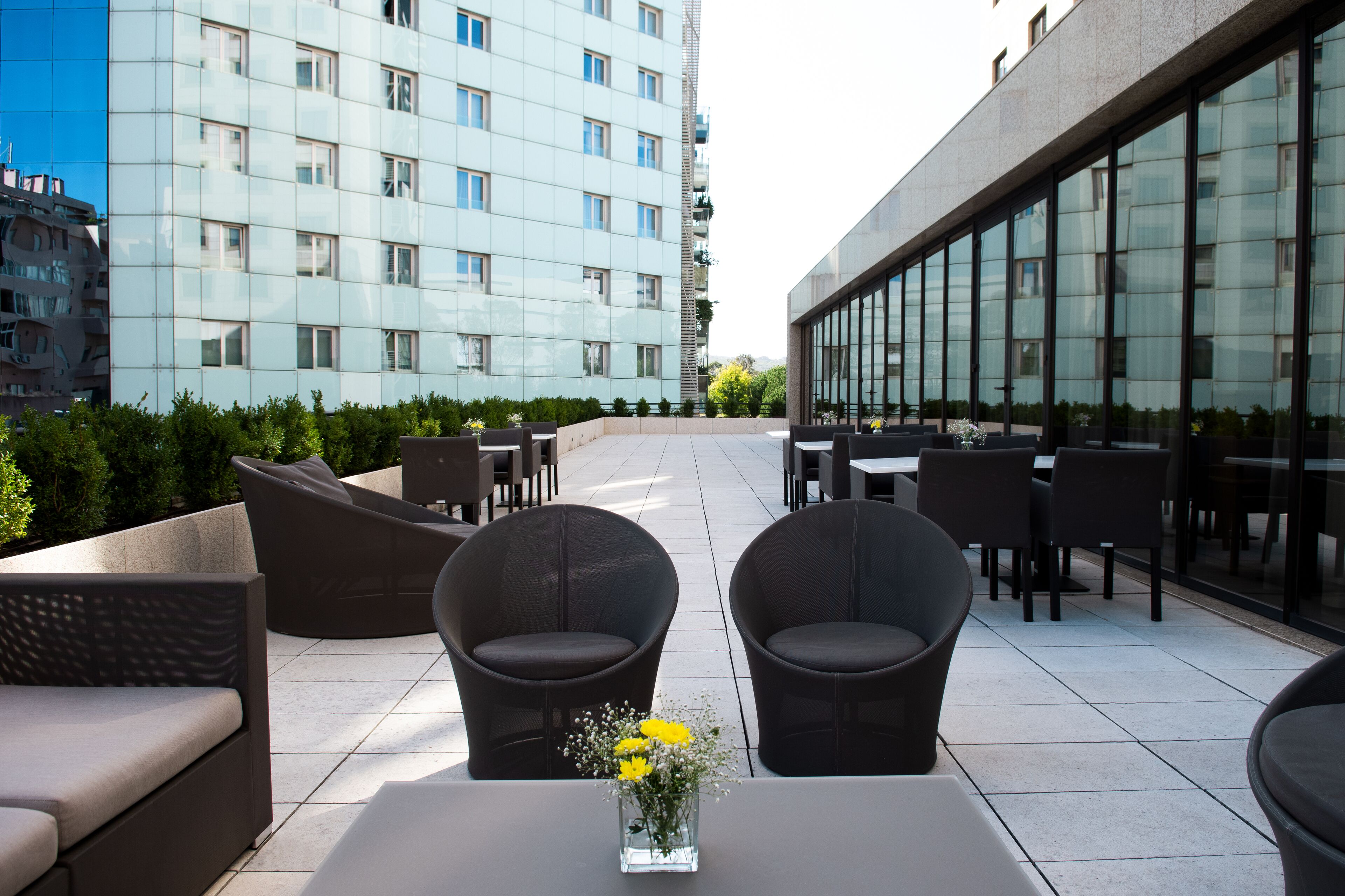 An outdoor seating area with modern furniture and a vase of flowers.