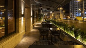 An outdoor cafe with tables and chairs, a pathway, and a view of the street. - SANA Metropolitan Hotel (Lisbon)