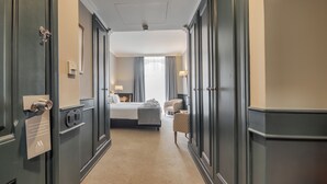 A hotel corridor leading to a room with a bed, a chair, and a desk with a lamp. - Hotel Metropole (Lisbon)