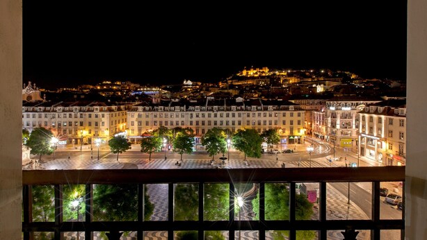 A nighttime cityscape with illuminated buildings and a hilltop castle. - Hotel Metropole (Lisbon)