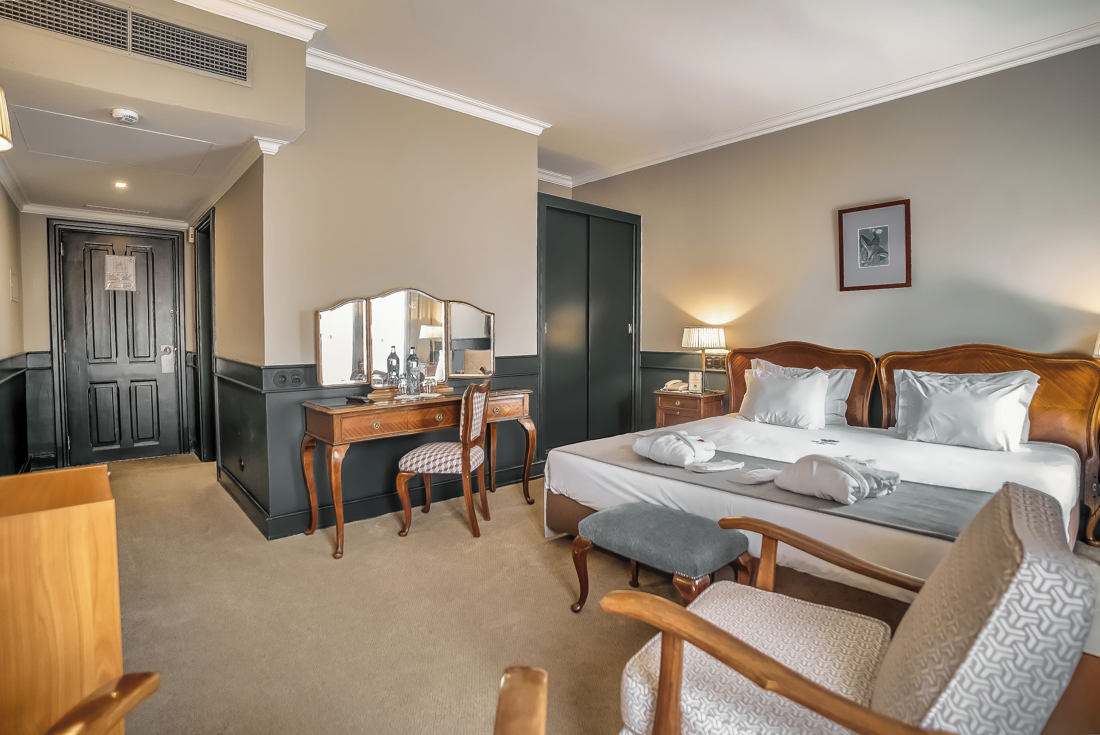 A hotel room with a bed, desk, chair, and a small table.