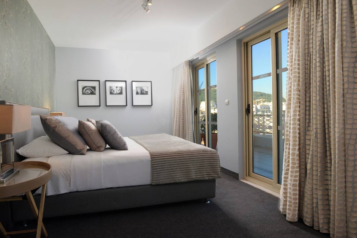 A bedroom with a bed, a bedside table, a lamp, and three framed pictures on the wall.