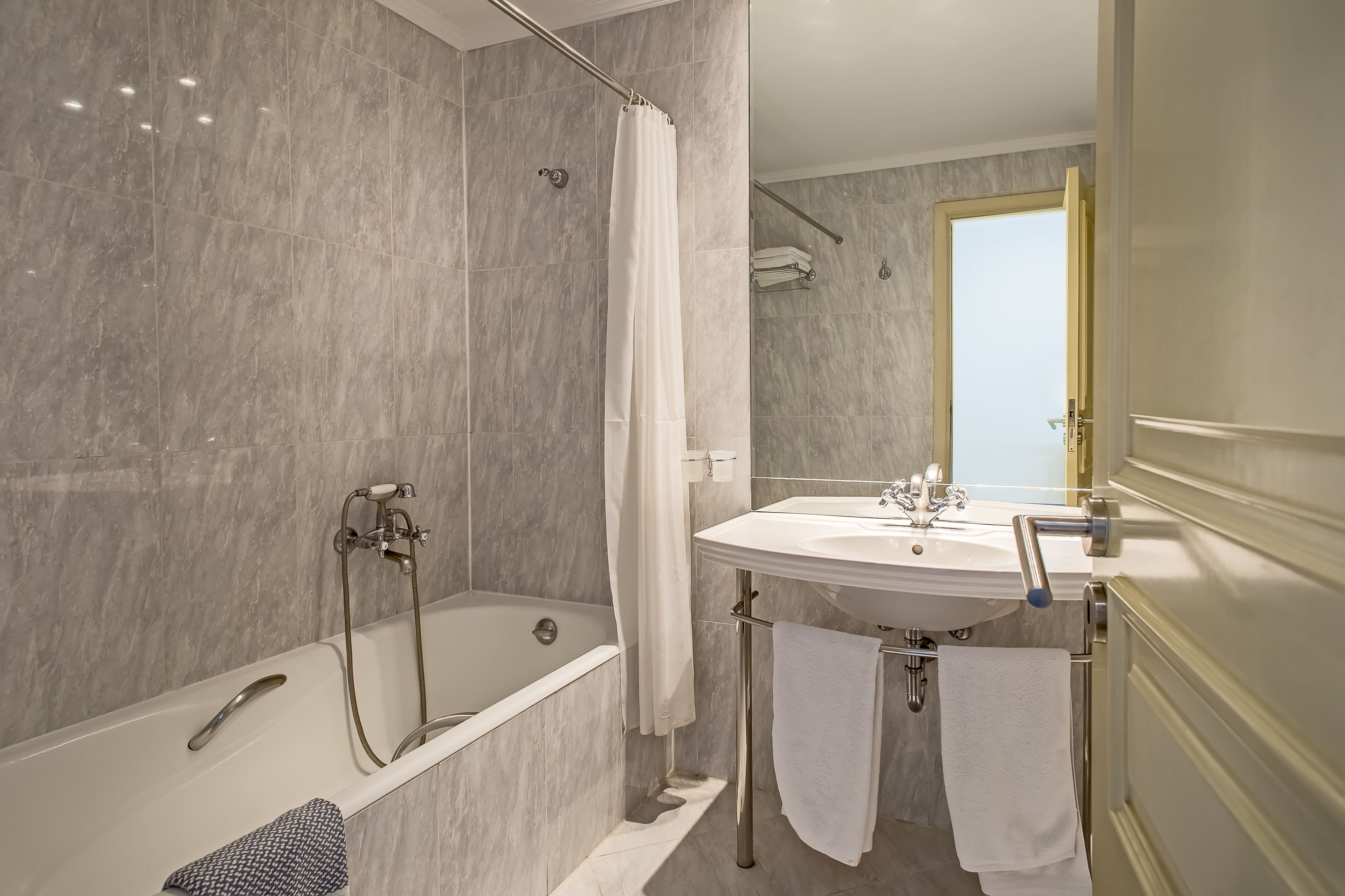 A modern bathroom with a bathtub, shower, and sink.