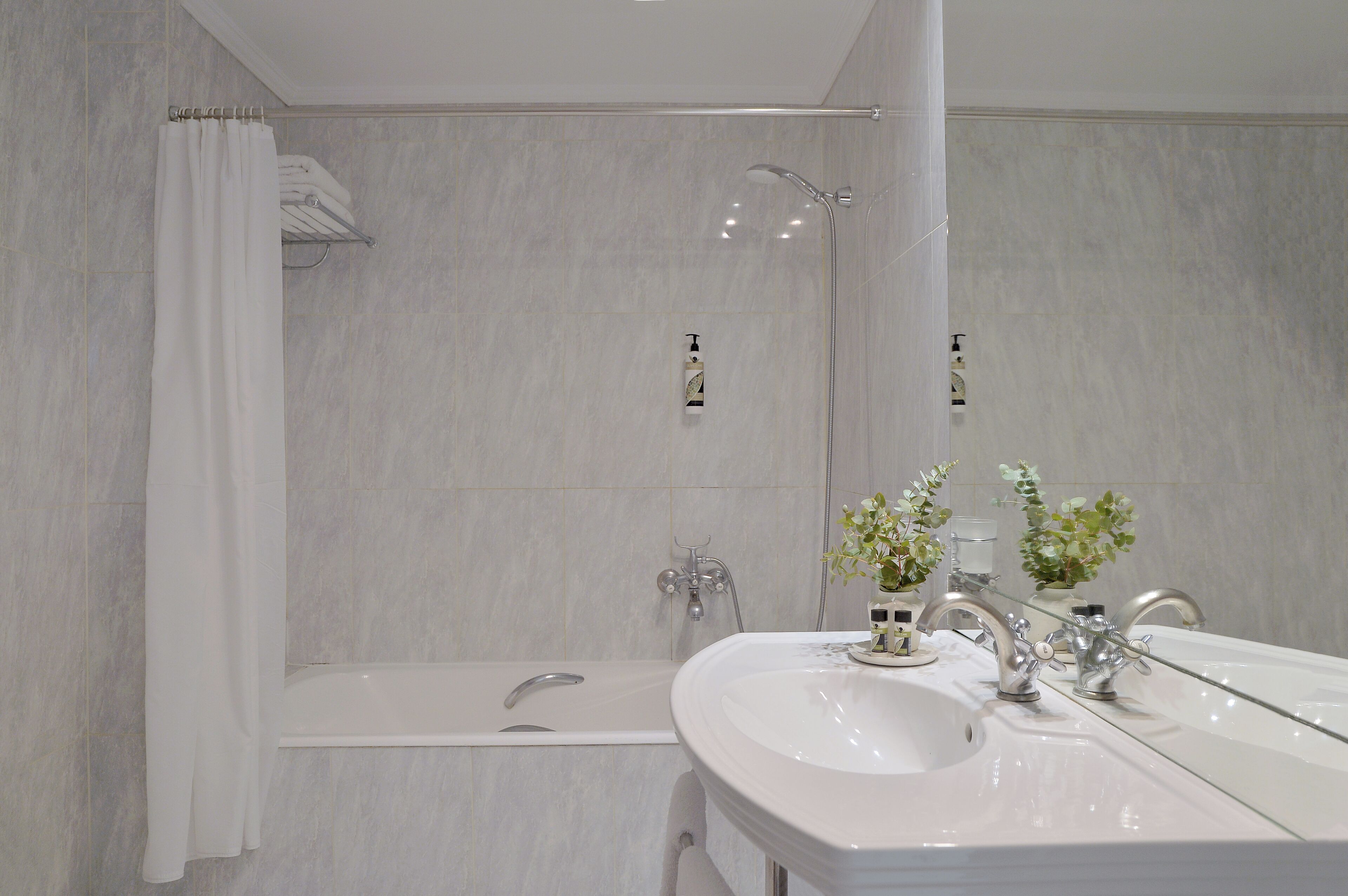 Un baño con bañera, lavabo con espejo y ducha.