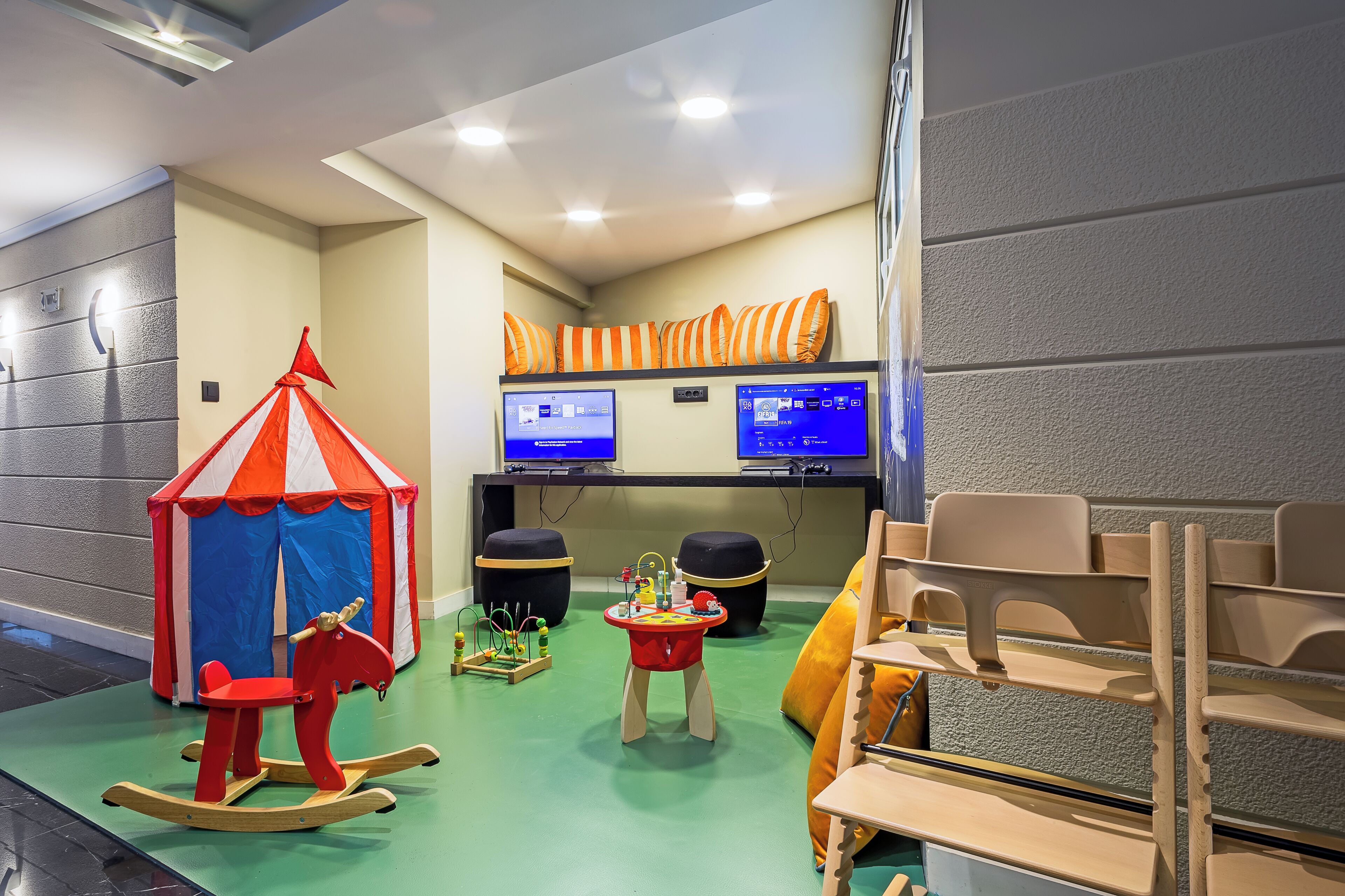 Un espace de jeux pour enfants avec un cheval à bascule, une petite table avec des jouets et une tente.