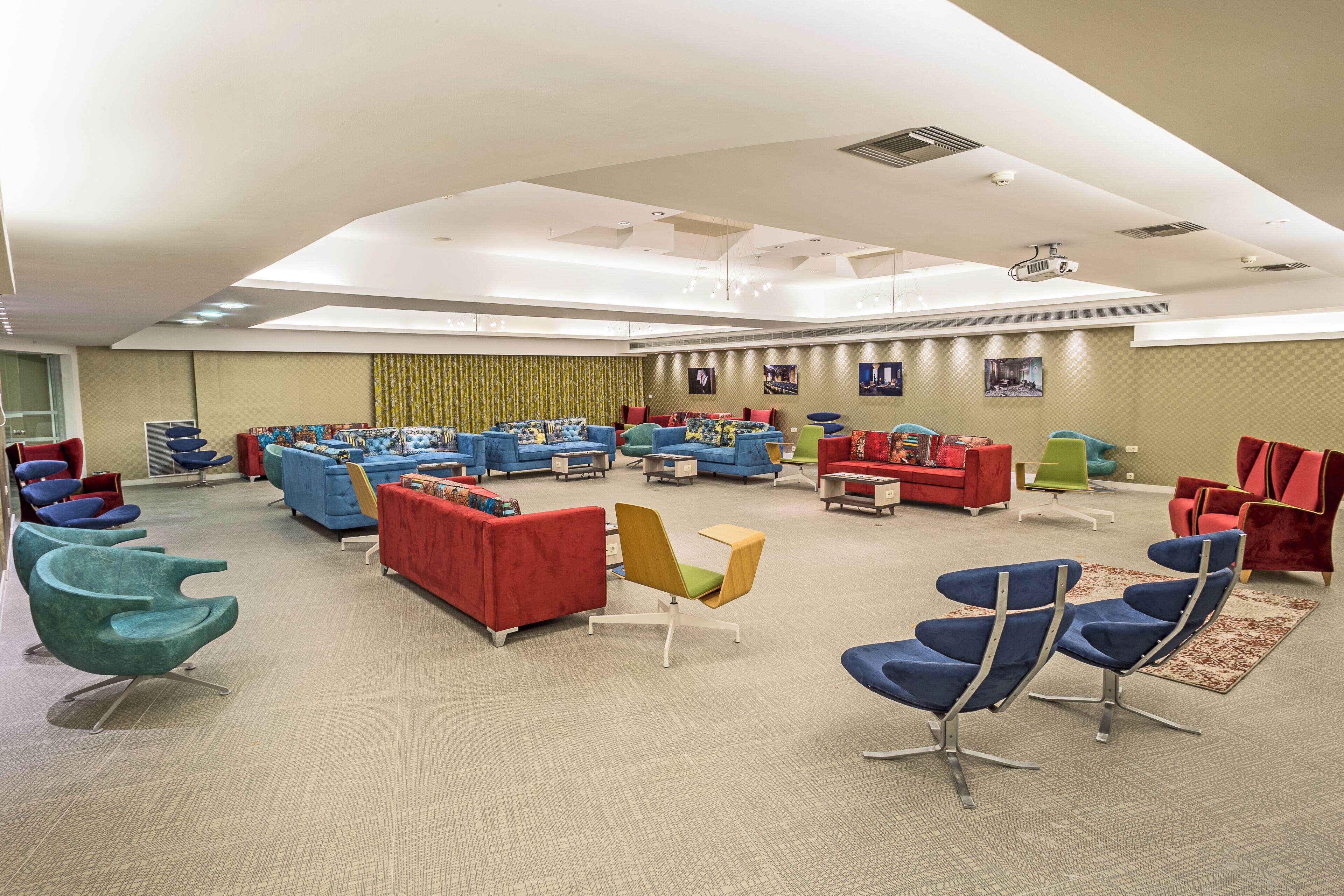A spacious room with multiple seating areas, including sofas and chairs, arranged in a semi-circle.