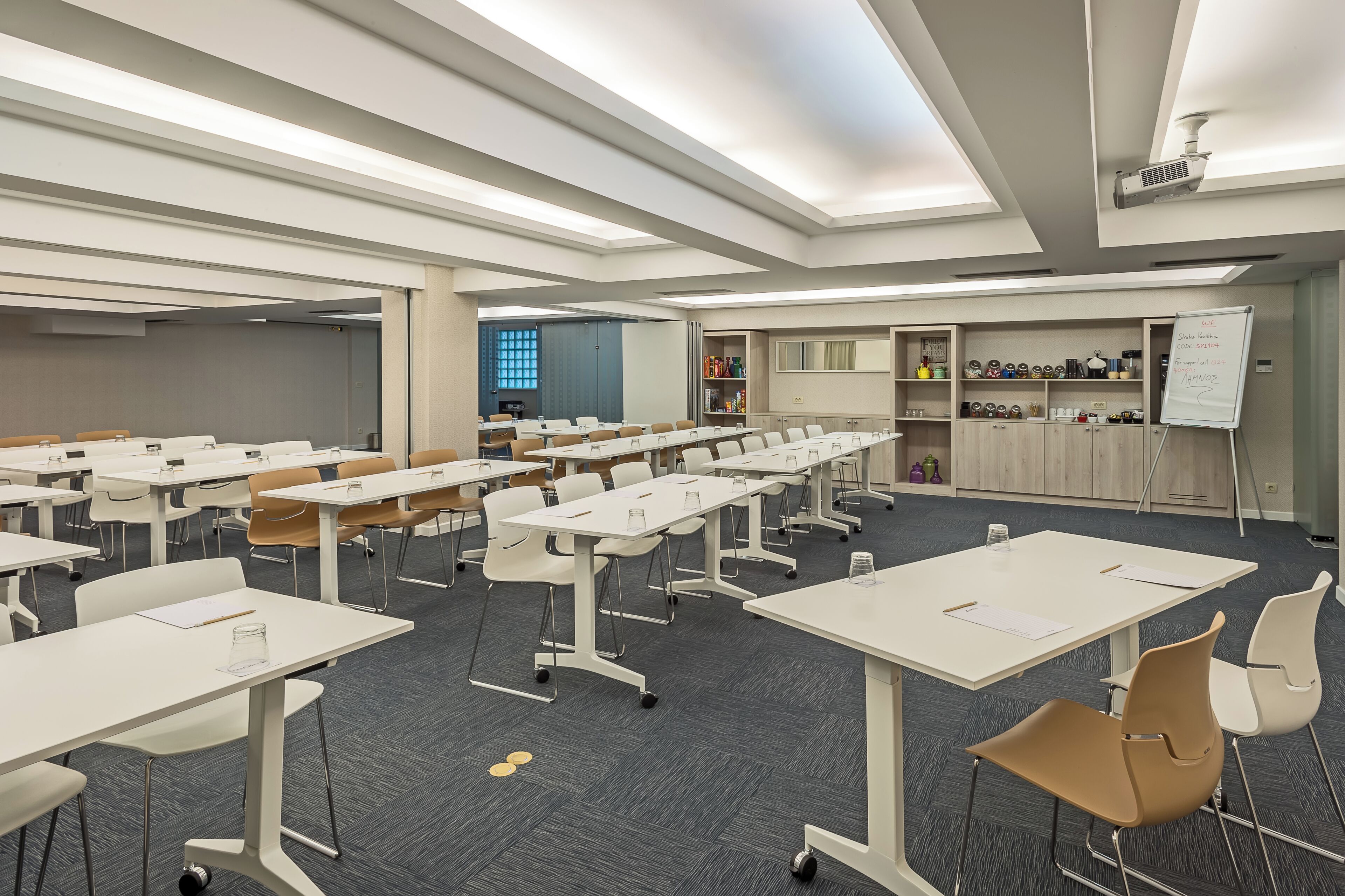 A conference room with white tables, chairs, and a whiteboard.