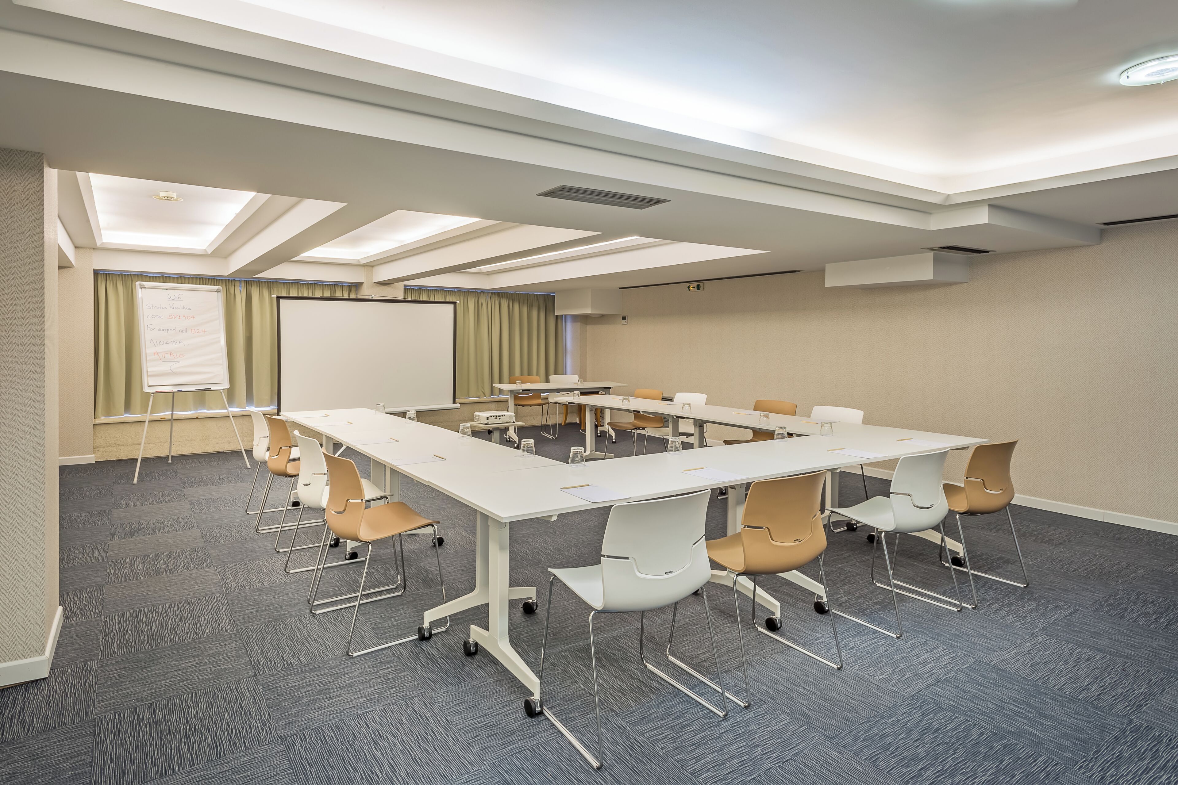A conference room with a white table, beige walls, and a grey carpet.