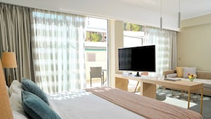 Habitación de hotel con cama, escritorio con televisor, sofá y vistas al exterior.
