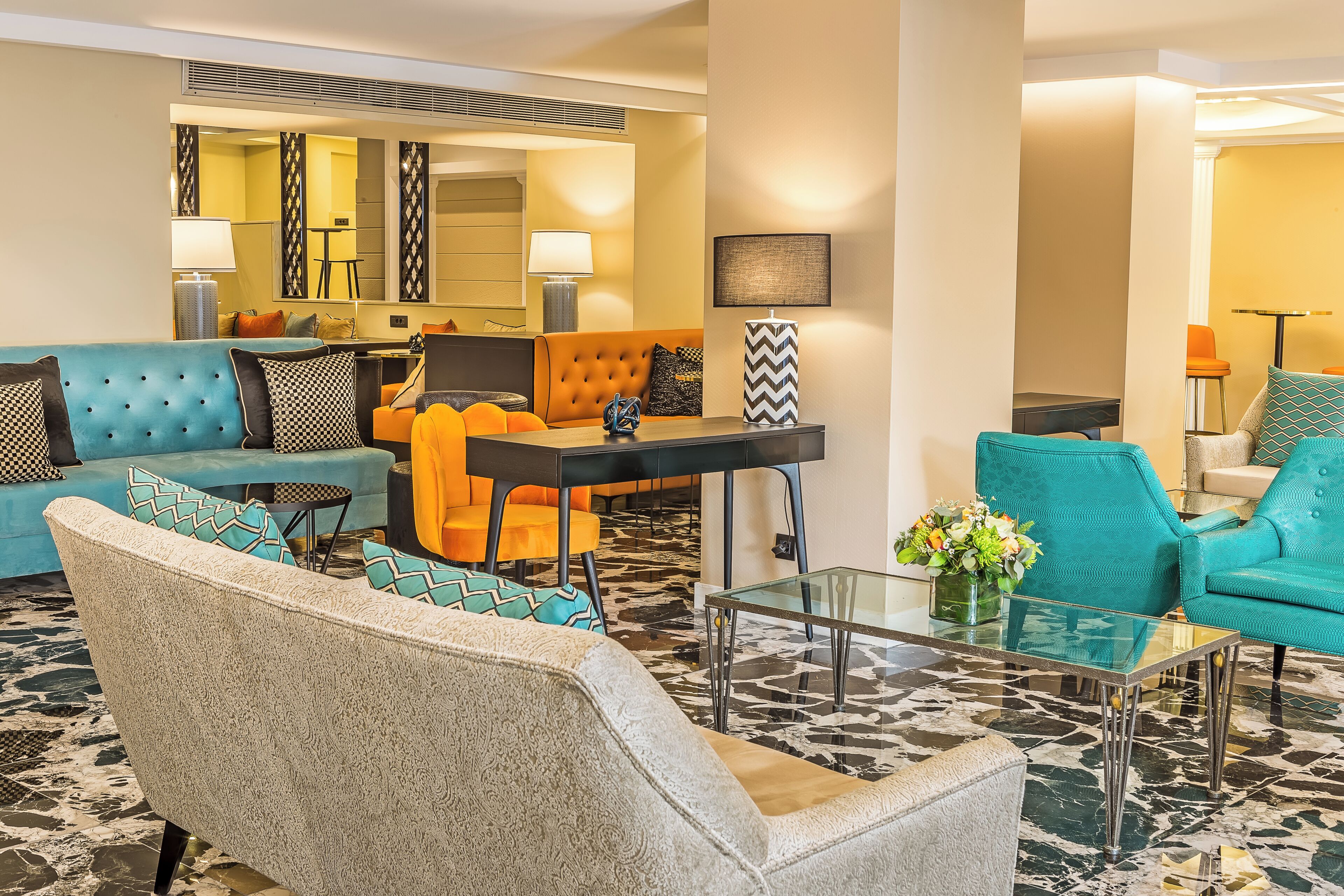 Un moderno vestíbulo de hotel con un sofá, sillones, una mesa de centro y un comedor.