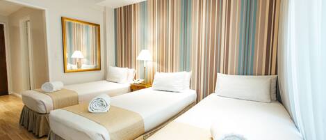 Habitación de hotel con dos camas, un espejo grande y cortinas a rayas.