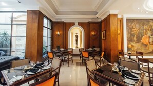 A restaurant with wooden paneling, a central statue, and a mural on the wall. - Dorá Hotel Buenos Aires (Buenos Aires)