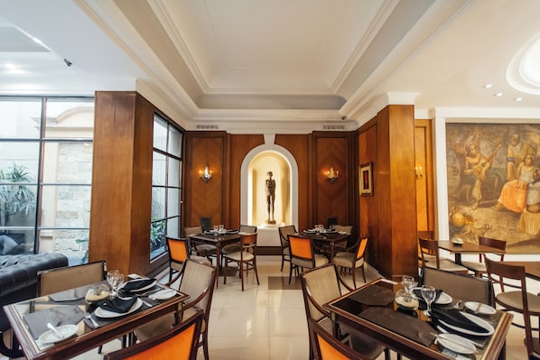 Un restaurante con paneles de madera, una estatua central y un mural en la pared.