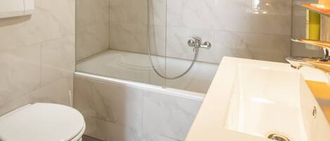A modern bathroom with a glass-enclosed shower, a bathtub, and a white sink.