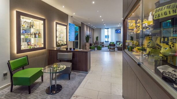 Un moderno hall de hotel con mostrador de recepción, zona de estar y una vitrina con peluches.