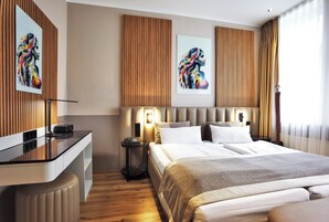 Una habitación de hotel moderna con una cama grande, un escritorio y obras de arte en las paredes.