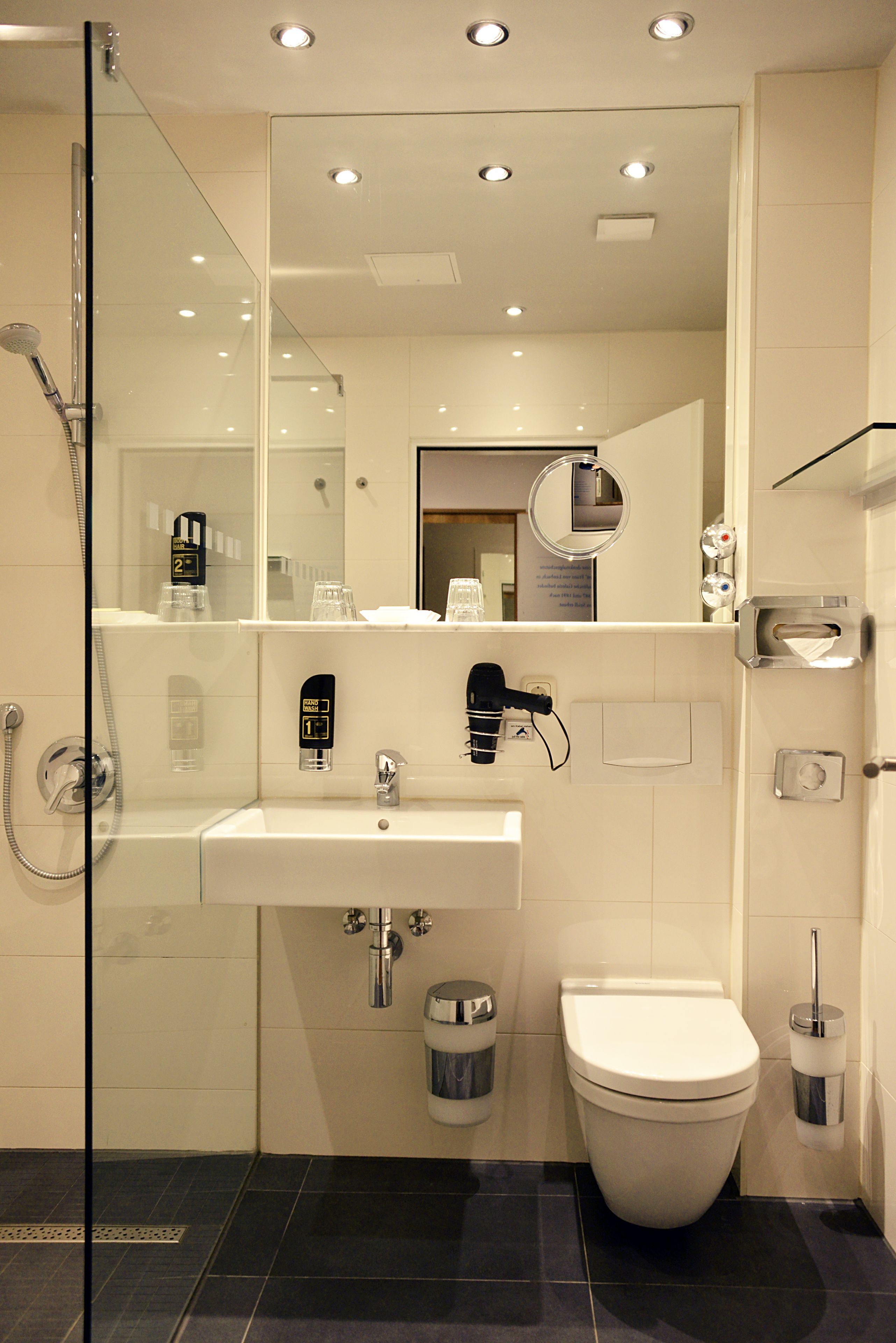 Ein modernes Badezimmer mit Duschkabine aus Glas, einem weißen Waschbecken und einer Toilette.
