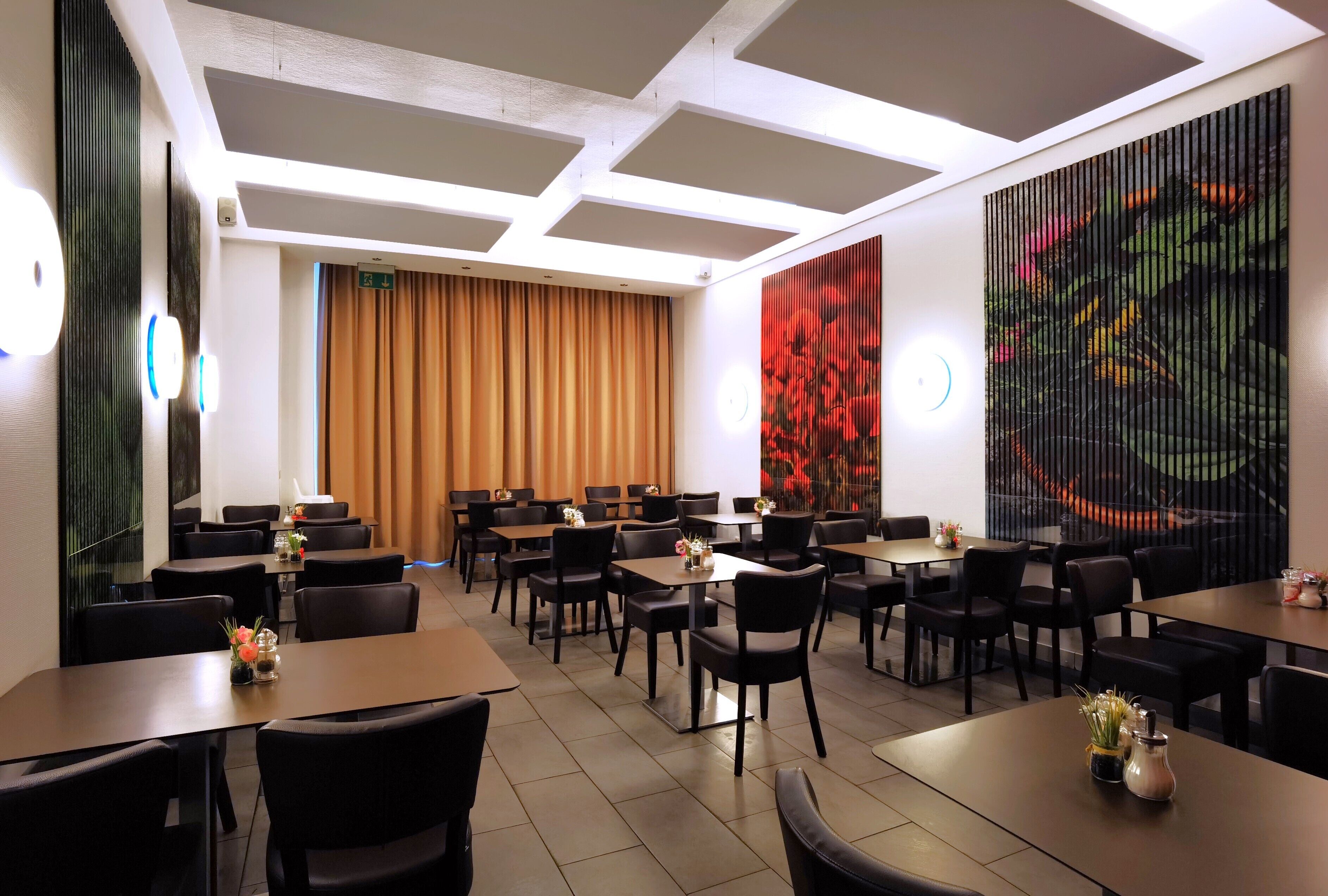 Ein Hotelrestaurant mit Tischen, Stühlen und einem großen, abstrakten Gemälde an der Wand.