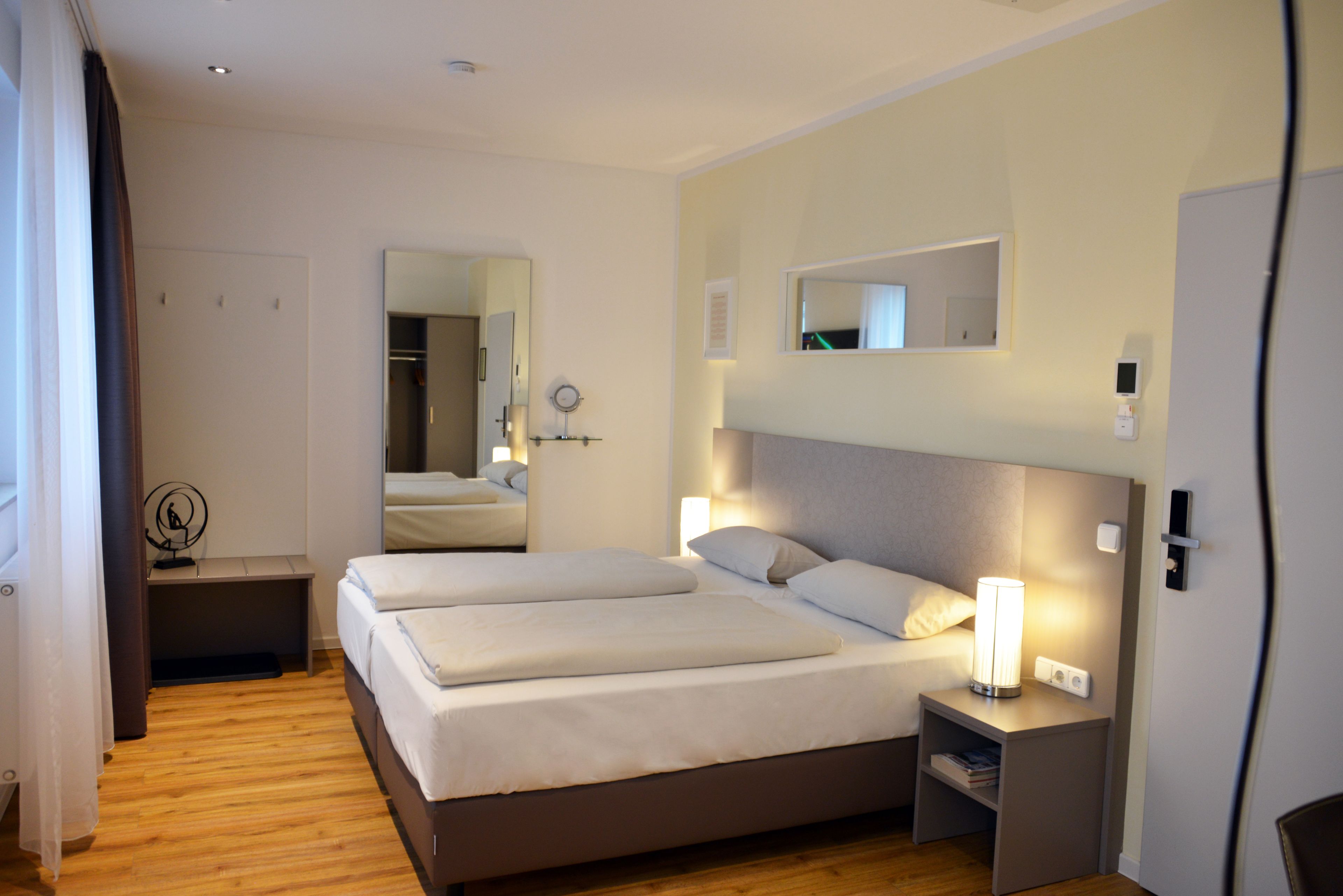 Une chambre d’hôtel avec un grand lit, des tables de chevet, un miroir et une armoire.