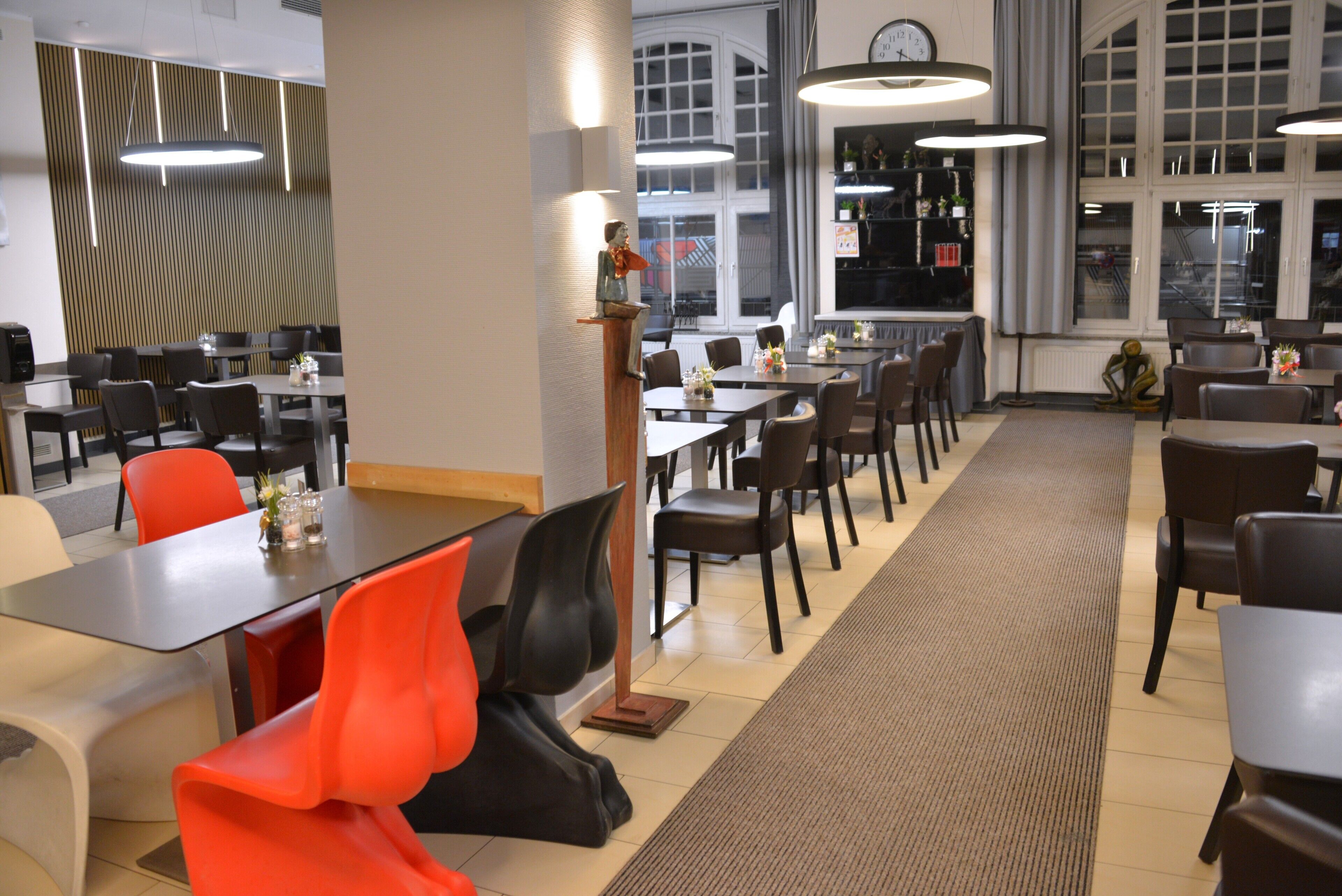 A modern dining area with multiple tables and chairs, a podium, and large windows.