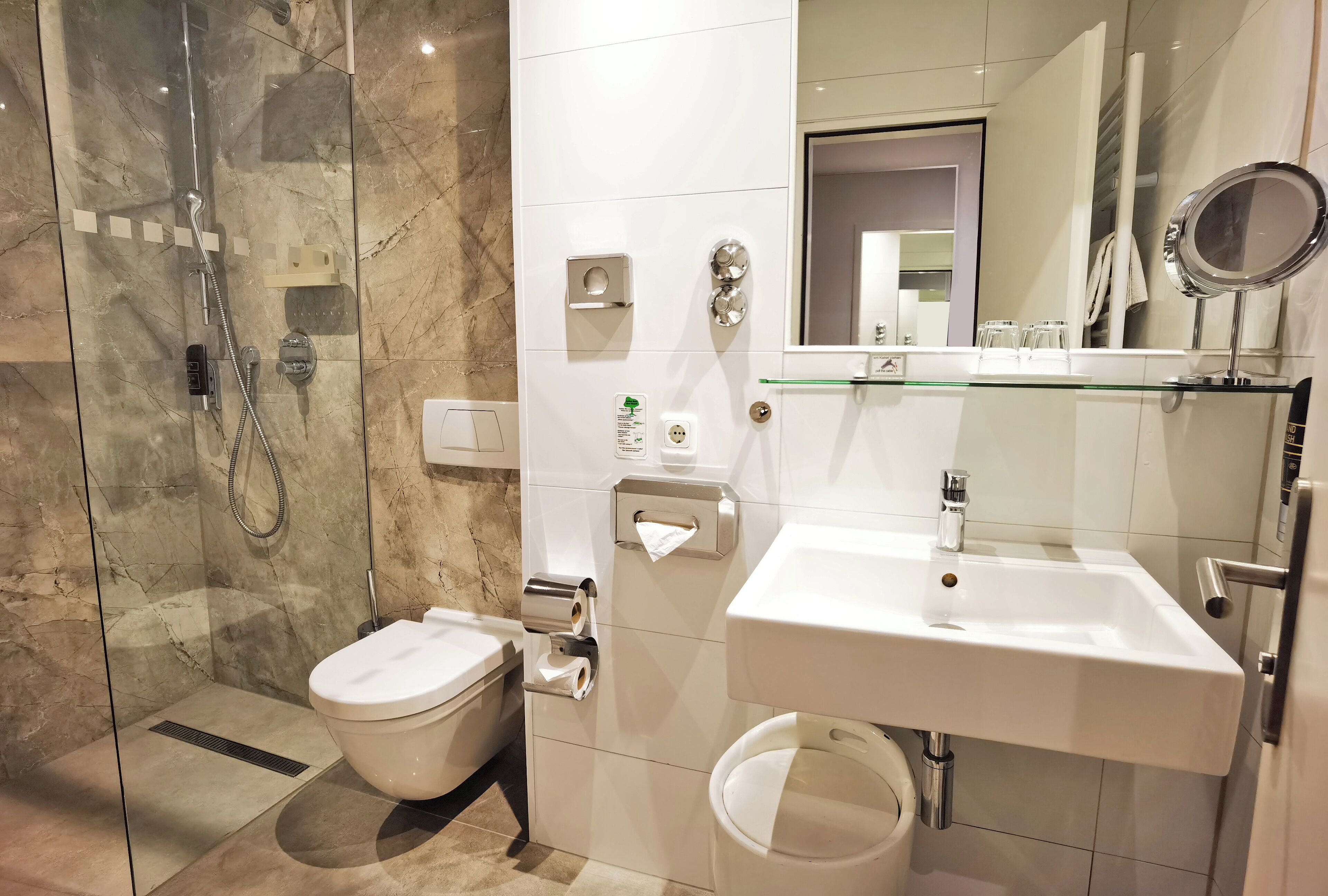 Ein modernes Badezimmer mit einer Duschkabine, Toilette, Waschbecken und Spiegel.