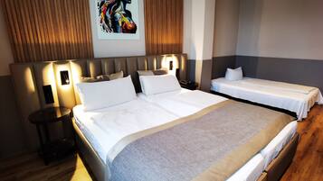 Une chambre d’hôtel avec un grand lit, un lit plus petit, une table de chevet et une œuvre d’art accrochée au mur.