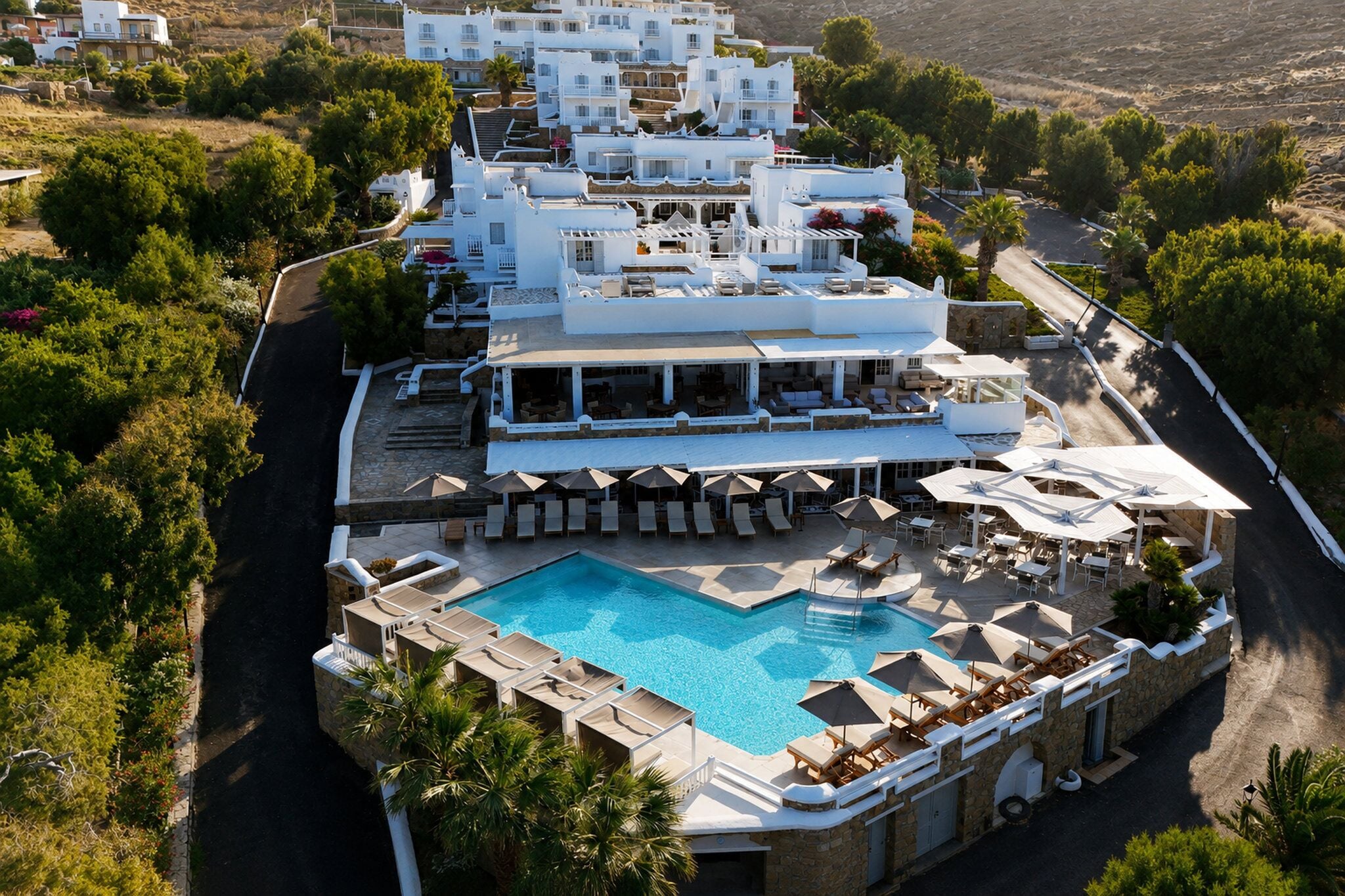 Un resort con piscina, sillones de descanso y un edificio blanco con varios balcones.