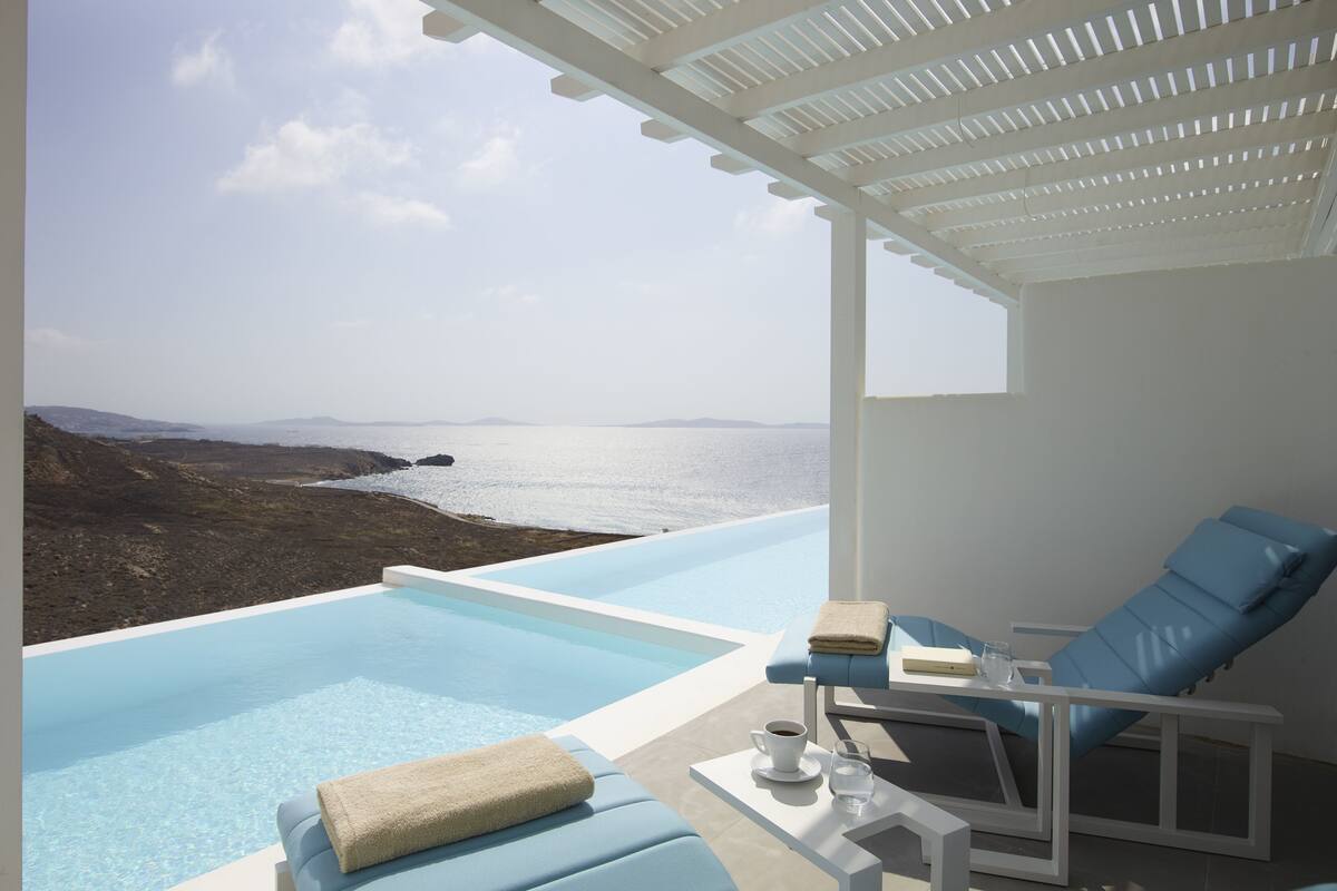 Zona de piscina exterior moderna con vistas despejadas al mar y a islas distantes.