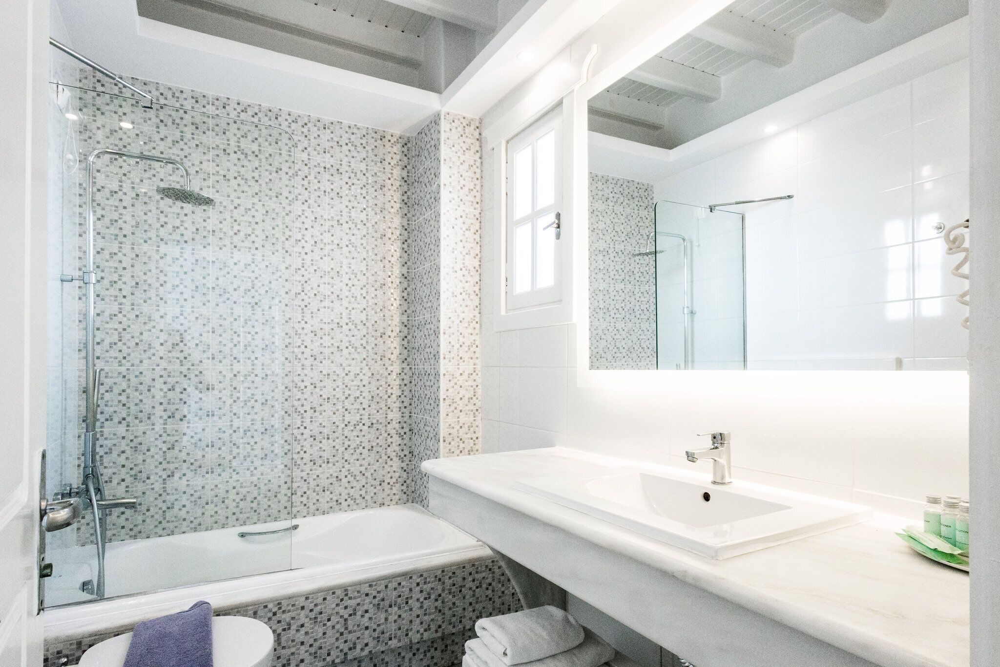 Ein modernes Badezimmer mit Duschkabine aus Glas, einer Badewanne und einem Waschtisch.