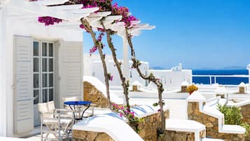 A white building with a stone wall, a blue table, and a white chair.