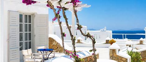 A white building with a stone wall, a blue table, and a white chair.