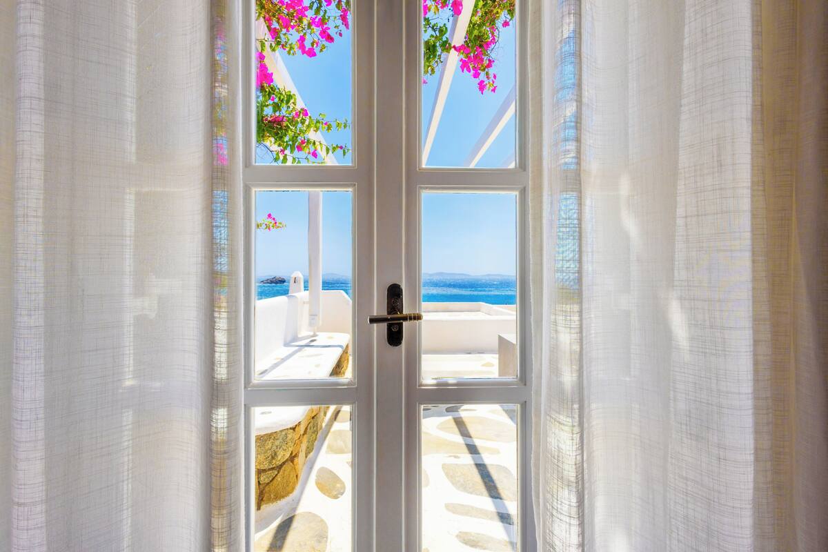 A white door with a view of a beach and clear sky.