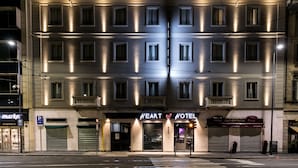 La façade d’un hôtel, ornée de nombreuses fenêtres, avec une enseigne bien visible indiquant « Heart Hotel » et une autre pour le restaurant « La Bistecca ».