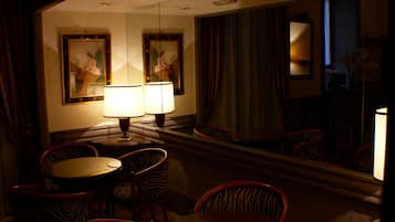 A hotel room with a dining area featuring zebra-striped chairs, a round table, and two wall-mounted lamps.