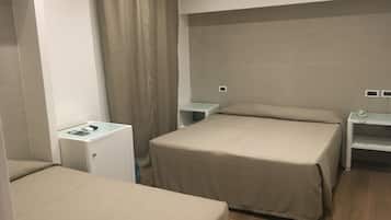 Una camera d'albergo con due letti, una scrivania, un comodino e una tenda.
