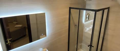 A modern bathroom with a glass shower enclosure, a sink with a mirror, and a toilet.