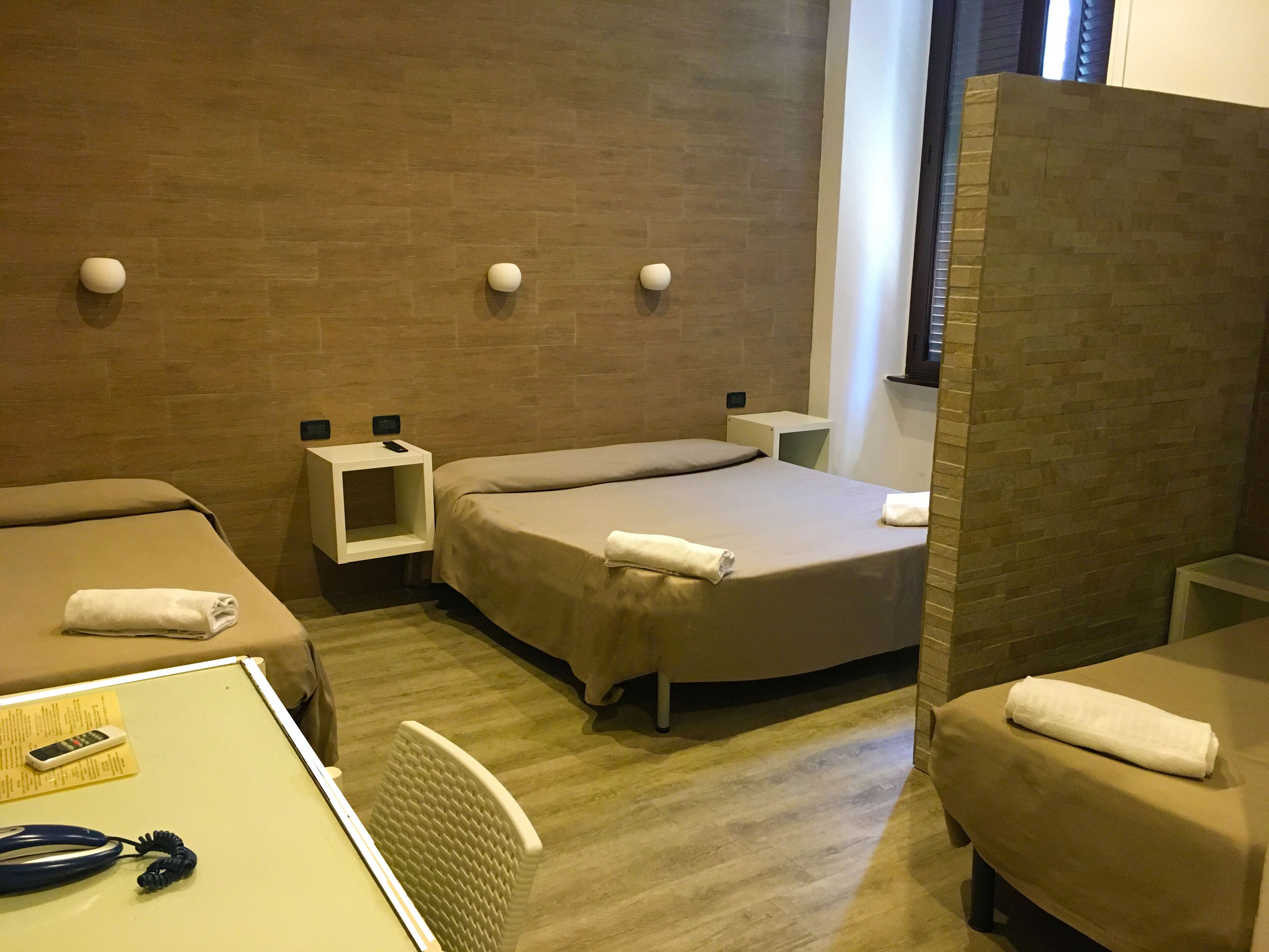 A hotel room with two beds, a small table with a telephone, and a chair.