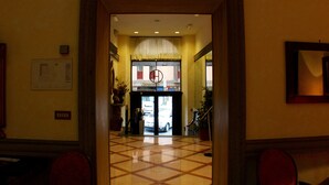 A hotel lobby with a tiled floor, a reception desk, and a framed picture on the wall. - Grand Hotel Olympic (Rome)