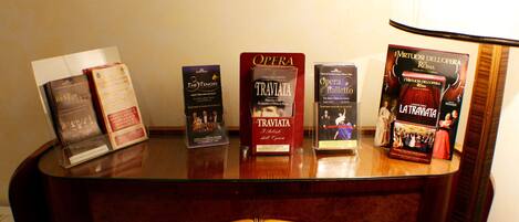 Un escritorio de madera con varios libros y folletos, incluyendo títulos como 'The Tenors' y 'Traviata'.